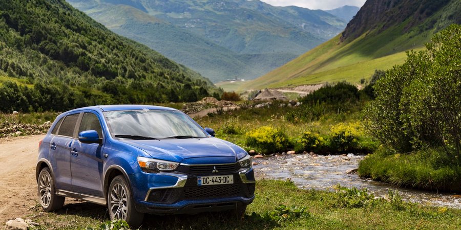 Rental car parked against Caucasus mountain backdrop in Georgia