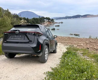 Frontansicht eines Mietwagens Toyota Yaris Cross am Flughafen Podgorica, Montenegro ✓ Auto Nr.15687. ✓ Automatisch TM ✓ 0 Bewertungen.